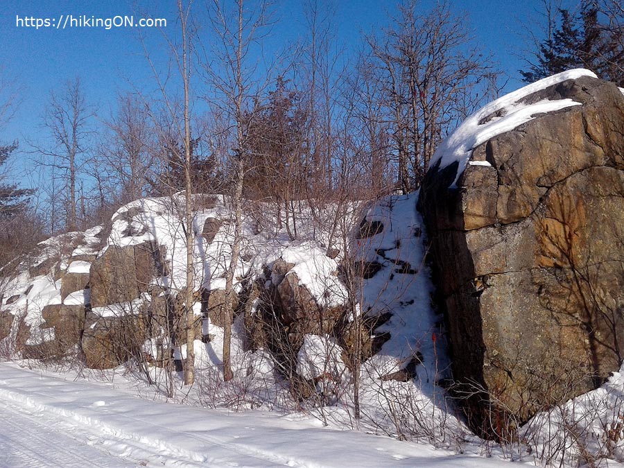 big rock on hiking trail covered in snow during wintertime